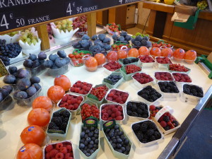 The fruit display at the produce market - mixed berries on the right, figs on the left, and something called kaki in the middle that looks like persimmons.