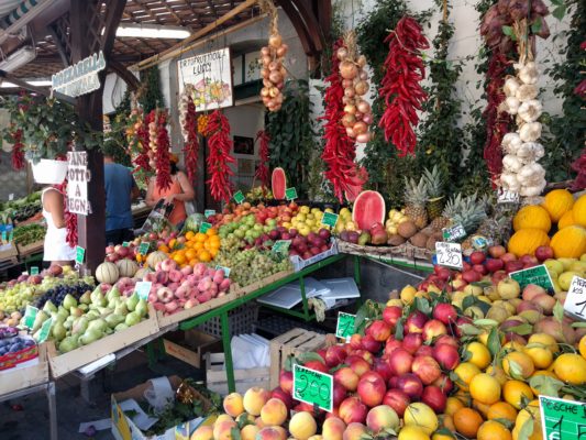 Sidewalk display of fruits and vegetables in front of a little grocery store