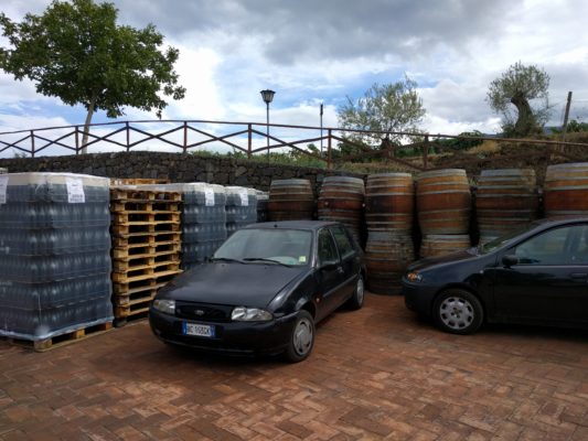 Empty barrels and bottles are stored on the patio outside the production building