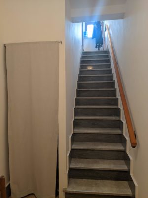 the stairs up to our apartment with a coat rack at the top - that curtain hides a little storage area with broom/mop/ironing board/etc