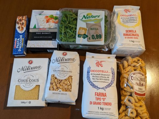 some groceries, clockwise from top left - anchovy paste (to spread on bread as an appetizer), basmati rice, arugula, semolina flour, savory crackers flavored with pepperoncini (hot peppers), wheat flour, and pasta and couscous from La Molisana which is a Molise brand of pasta made in Campobasso