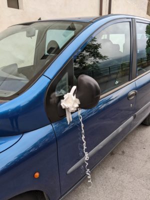 one of the cars of the wedding party bedecked in ribbons